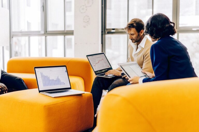 Business professionals in a modern office working together in front of laptops and charts, discussing SEO and online marketing strategies