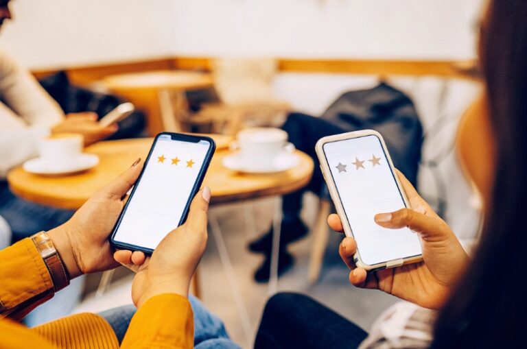 Άτομα που ελέγχουν τις online αξιολογήσεις στα smartphone τους σε ένα καφέ