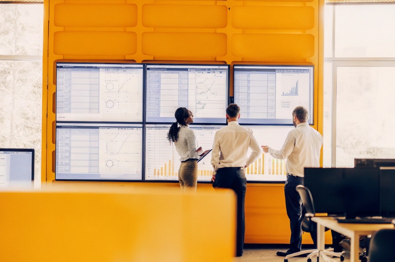 Επαγγελματίες σε γραφείο εξετάζουν γραφήματα ΑΙ για τις τάσεις βελτιστοποίησης μηχανών απάντησης το 2026 στην επιχείρηση TWO DOTS