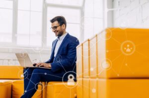 Νεαρός επιχειρηματίας σε σύγχρονο γραφείο χρησιμοποιεί laptop με εικονίδια τεχνητής νοημοσύνης, απεικονίζοντας τον ανταγωνισμό στις μηχανές αναζήτησης