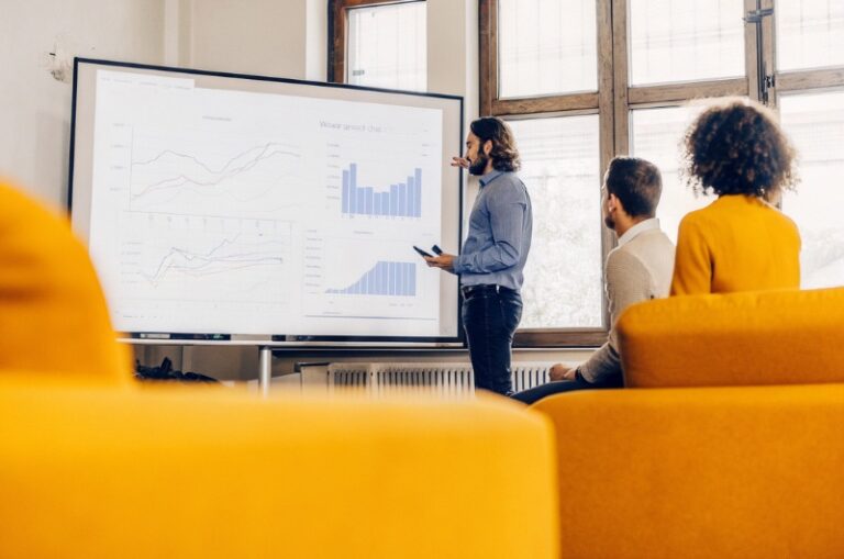 Επιχειρηματίες σε αίθουσα συσκέψεων συζητούν τη μείωση της επισκεψιμότητας και τον ρόλο των Google AI Overviews παρουσιάζοντας διαγράμματα