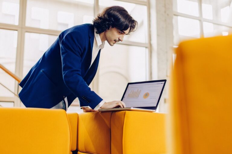 A young professional sits at a desk and analyses website statistics on his computer
