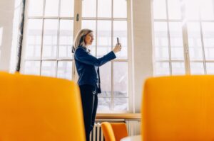 Young businesswoman holds her mobile phone and records a short video in a bright office
