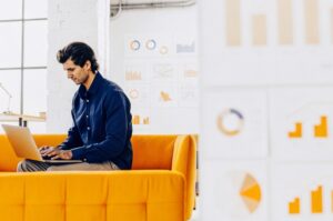 Млад предприемач използва инструменти за цифров маркетинг в офиса си, представяйки марката TWO DOTS