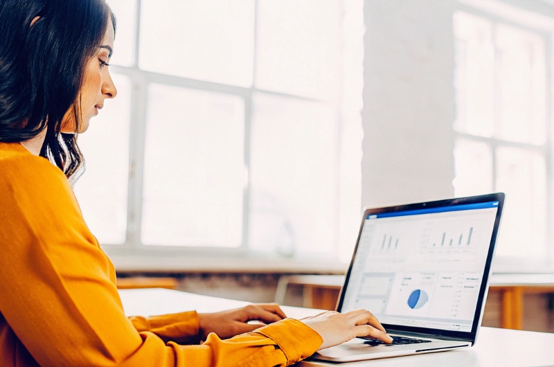 Professional woman working on Google Analytics dashboard in TWO DOTS office, optimizing Google Analytics reports