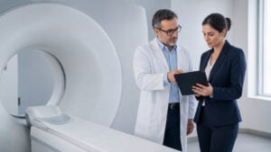 Ακτινολόγος και ειδικός AI αξιολογούν workflow τρισδιάστατης ακτινολογίας δίπλα σε αξονικό τομογράφο